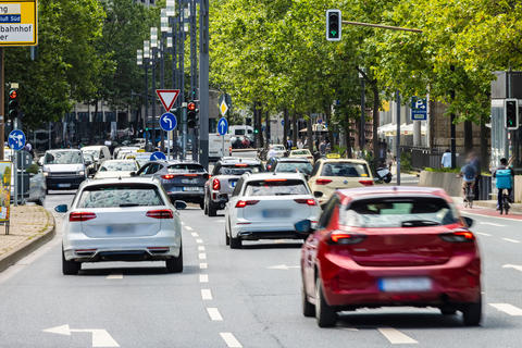 Viele Autos im dichten Stadtverkehr an einer Ampel, städtische Geräuschkulisse und Hektik.