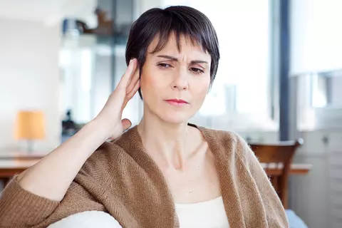 Frau hält sich das Ohr