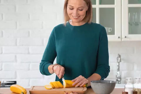 Eine Frau schneidet in der Küche Gemüse auf einem Brett