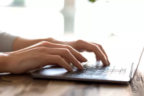 Nahaufnahme zweier Hände, die auf einer Laptop-Tastatur tippen.