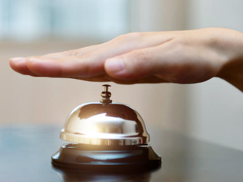 Flach ausgestreckte Hand die gerade auf eine Tischglocke schlägt