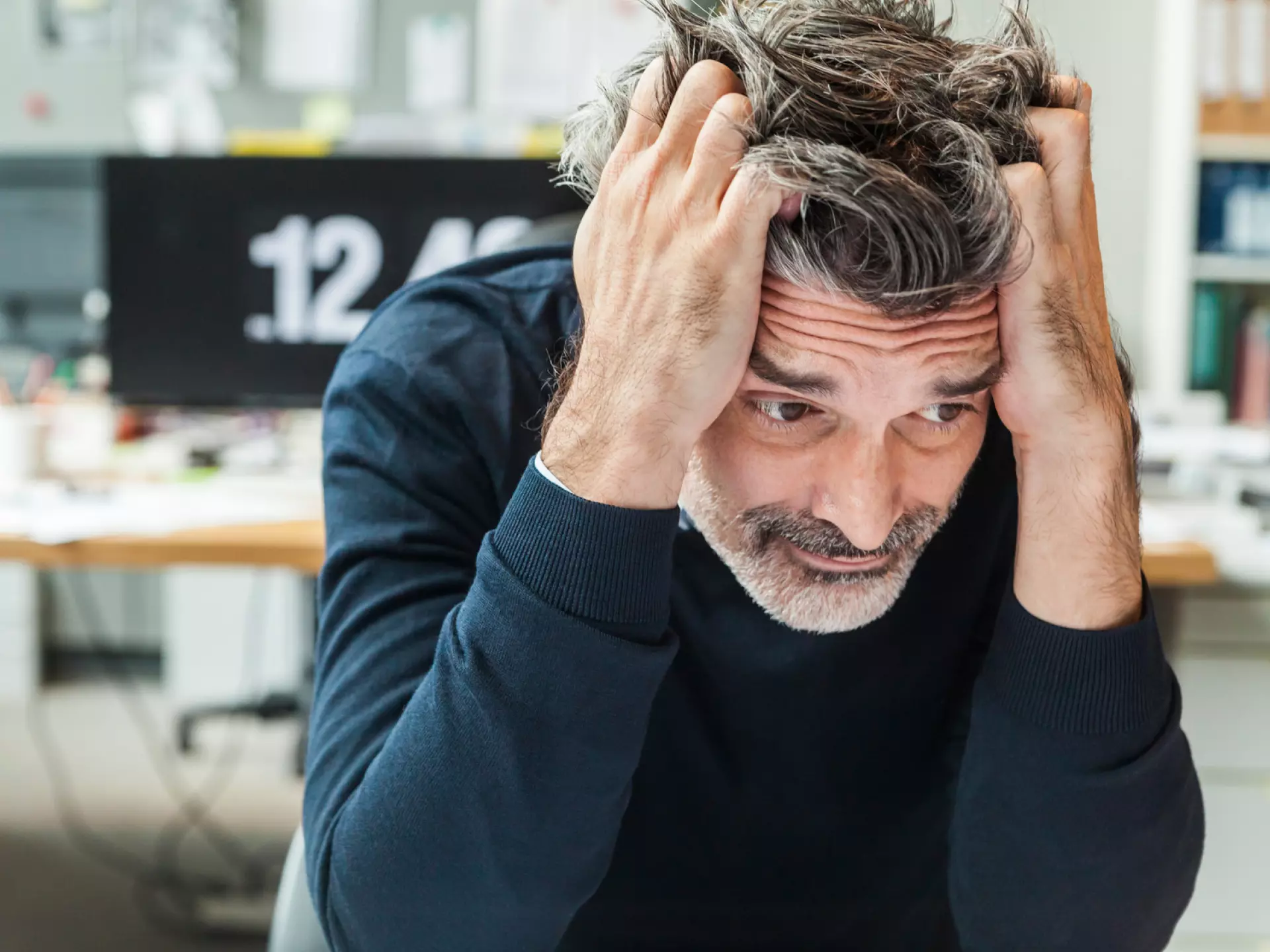 Gestresster Mann, der seinen Kopf in die Hände stützt